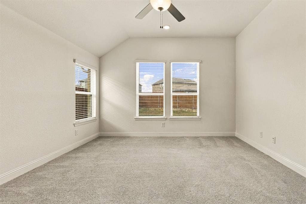 Room featuring neutral wall tones, plush wall-to-wall carpeting, three multi-pane windows, and a ceiling-mounted light fixture with a fan