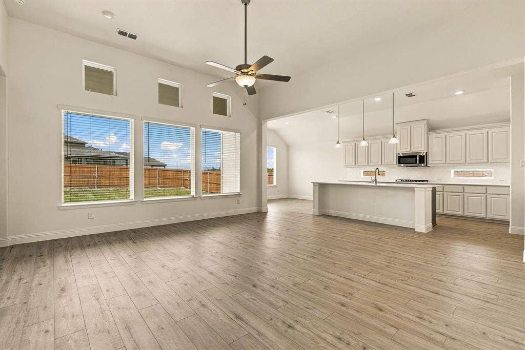 Vaulted ceilings, wood-finish flooring, oversized windows with transoms, kitchen island with built-in cabinetry, and pendant lighting