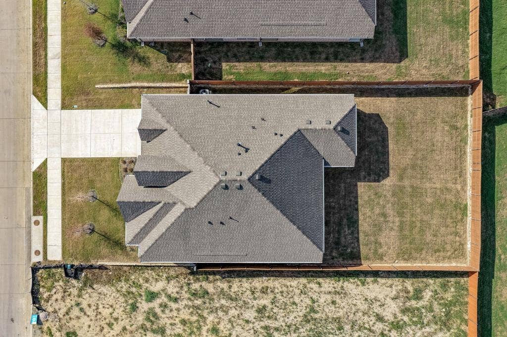 Aerial perspective featuring a multi-faceted roofline, a private fenced-in rear yard, a concrete driveway, and direct street access