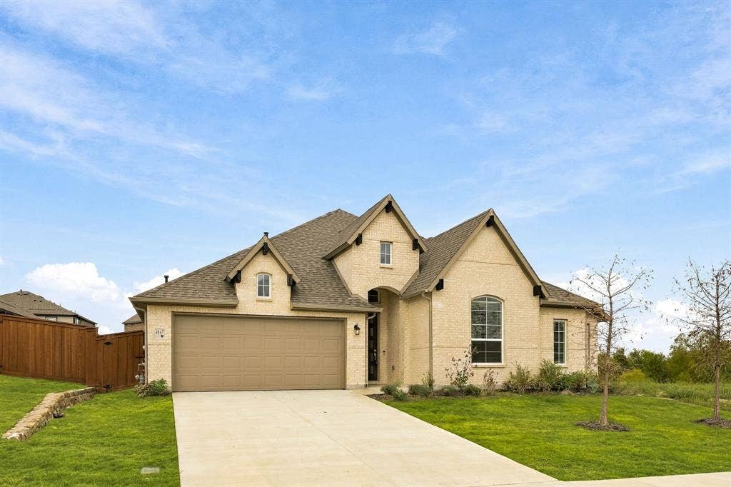 Brick and stone facade featuring a multi-gabled roofline, an attached two-car garage, and a concrete driveway