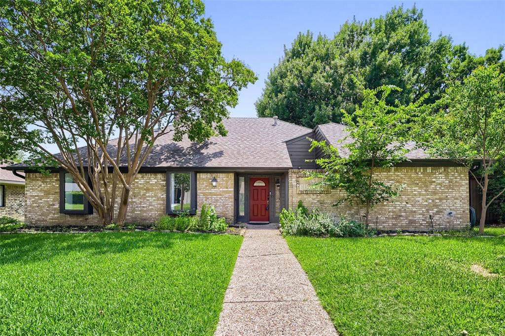 6234 La Cosa Drive, Dallas, TX 75248 Brick exterior with dark trim, a red entry door, and a shingle roof