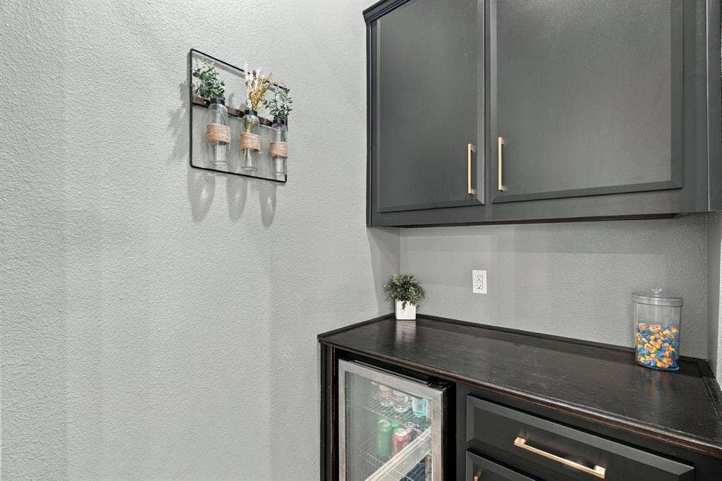 Convenient built-in cabinetry with upper storage, countertop space, drawers, and an undercounter beverage refrigerator.