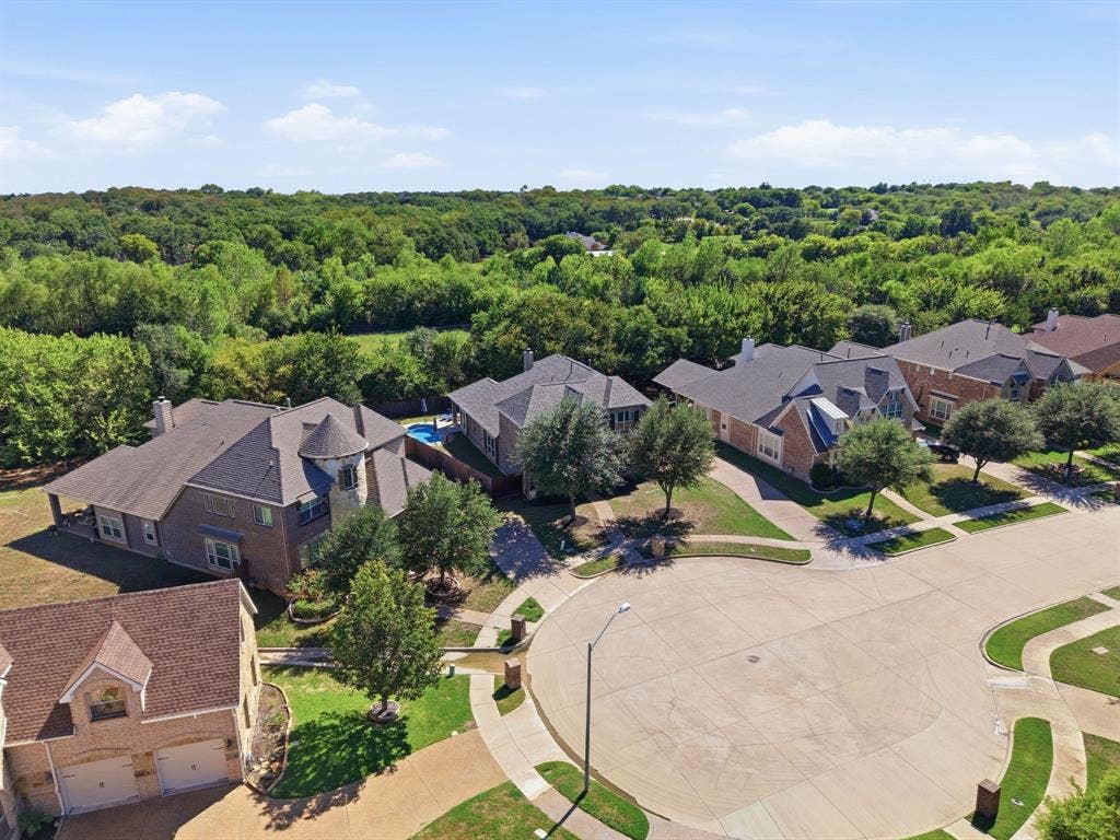 Elevated view showcasing the home's location at the end of a cul-de-sac with a wooded backdrop behind the property.