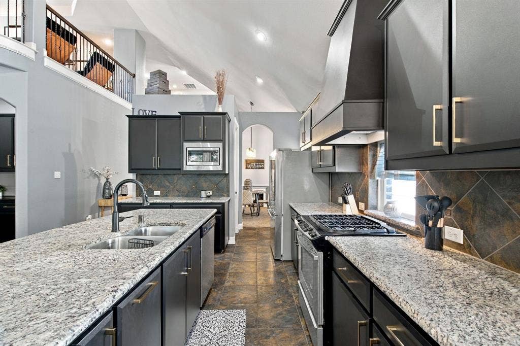 Generous counter space, a gas cooktop, stainless steel appliances, and a large island with a double-basin sink make this kitchen both practical and inviting.
