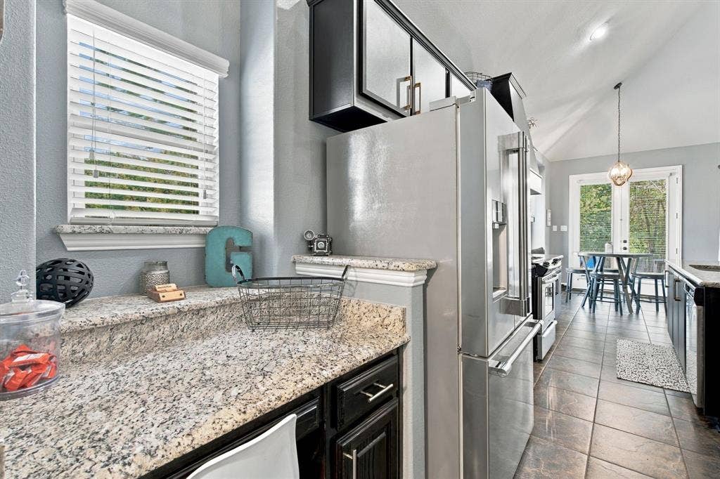Additional counter and cabinet space beside the stainless steel refrigerator provides convenient storage and prep space that can serve as a butler's pantry or sitting desk, with a nearby breakfast nook overlooking the backyard.