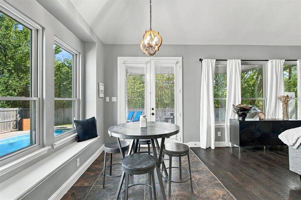 Bright breakfast area featuring a charming window seat, decorative pendant lighting, and French doors opening toward the backyard and pool.