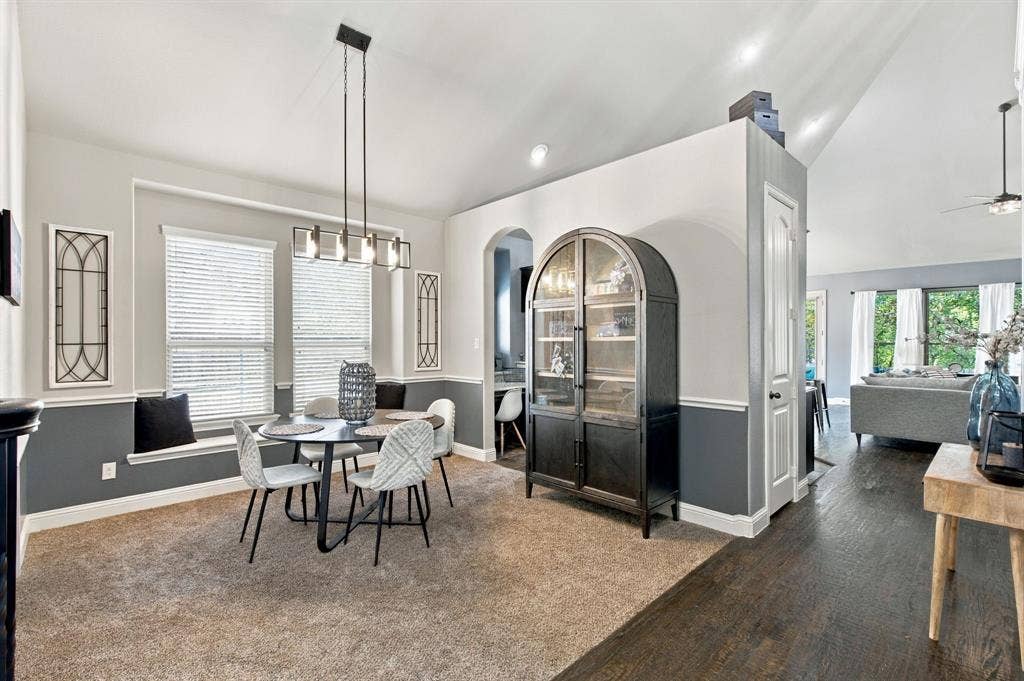 Dedicated dining space with elegant wainscoting, a contemporary chandelier, and a built-in window seat beneath two large windows.