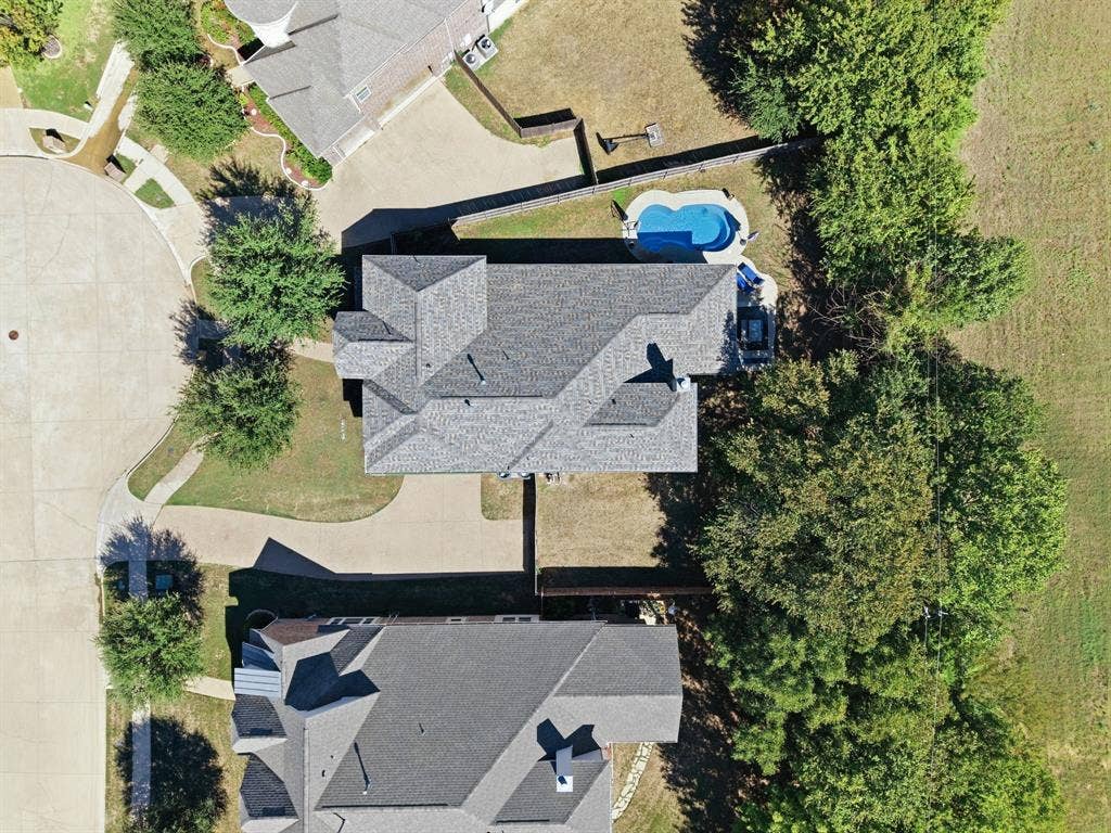 Bird's-eye view of the property showcasing the home's footprint, driveway, fenced backyard, and private swimming pool.