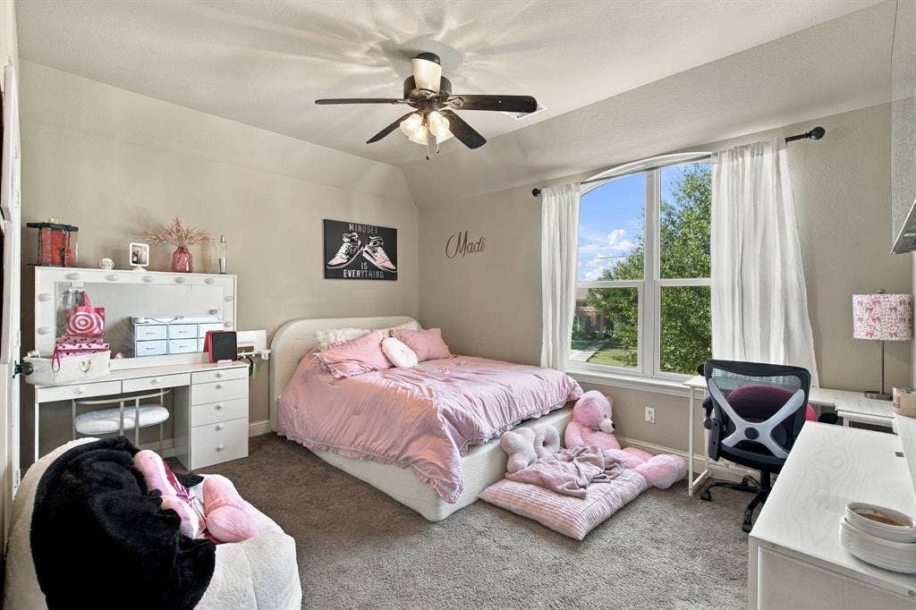 Bright upstairs bedroom with a large arched window, ceiling fan, and plenty of space for bedroom furniture, a desk, or a personal sitting area.
