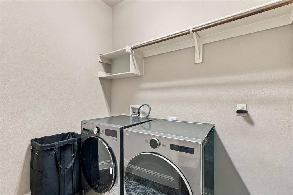 Dedicated spacious laundry room with full-size washer and dryer, overhead shelving, and hanging space for added convenience.