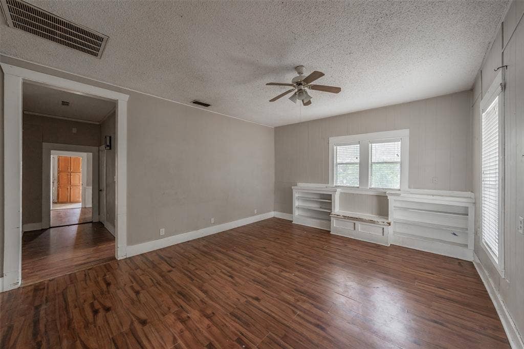 212 N Ruddell Street, Denton, TX 76205 Wood-finish flooring, built-in shelving, two windows with white trim, and a ceiling fan with light fixture