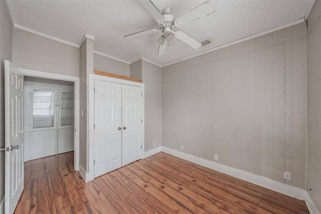 212 N Ruddell Street, Denton, TX 76205 Hardwood-finish flooring throughout, white ceiling fan, crown molding, white paneled doors, and built-in cabinetry with glass panels