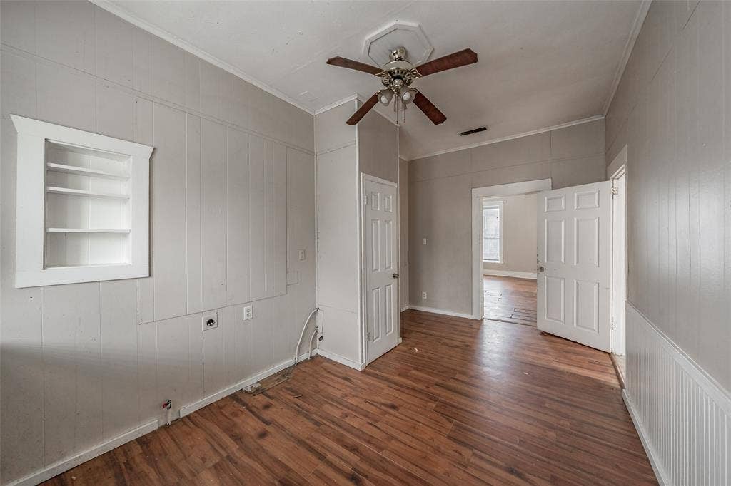 212 N Ruddell Street, Denton, TX 76205 Wood-finish flooring, built-in shelving, paneled walls, and a ceiling fan with light fixture