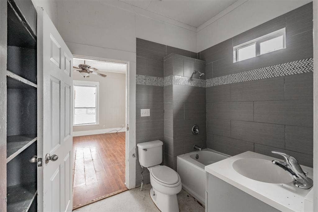 212 N Ruddell Street, Denton, TX 76205 Bathroom featuring a tiled shower surround with decorative accent, single vanity, and built-in shelving