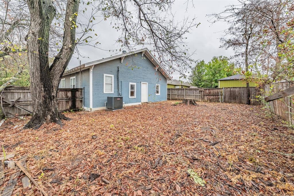 212 N Ruddell Street, Denton, TX 76205 Blue siding exterior, multiple windows, external HVAC unit, wood fencing, mature trees
