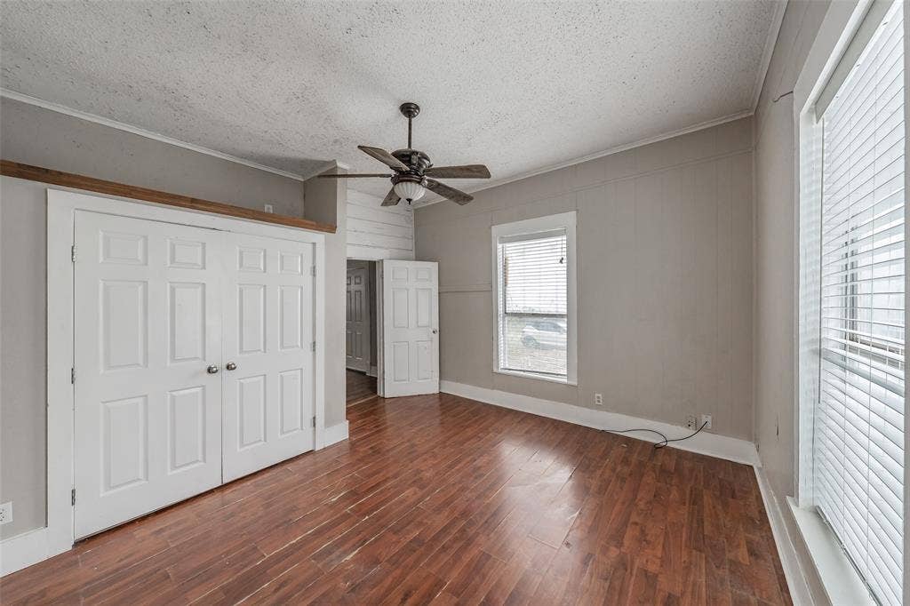 212 N Ruddell Street, Denton, TX 76205 Wood-finish flooring, white panel doors, a ceiling fan with light fixture, and multiple windows with blinds