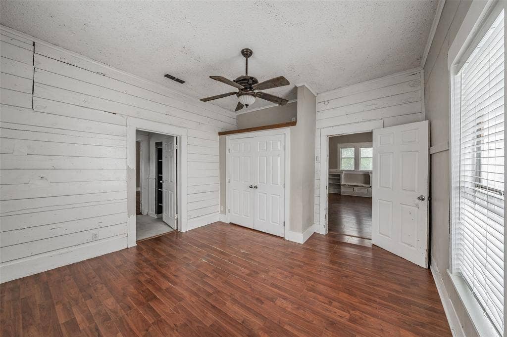 212 N Ruddell Street, Denton, TX 76205 Wood-finish flooring, white shiplap walls, ceiling fan with light fixture, and white bi-fold closet doors