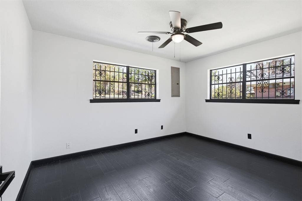 2313 Clearview Drive, Fort Worth, TX 76119 Dark wood-finish flooring, white walls, and two windows with decorative security grilles