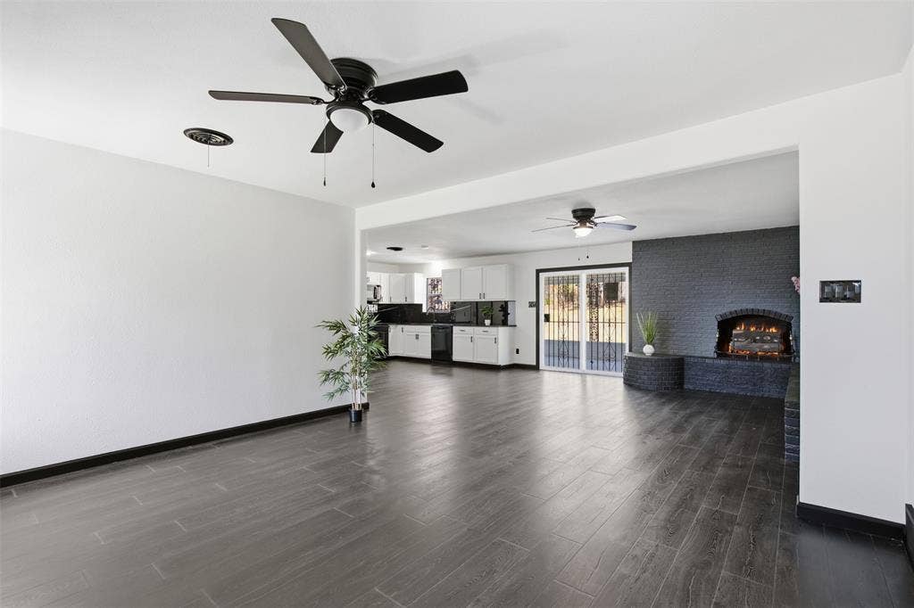 2313 Clearview Drive, Fort Worth, TX 76119 Open concept living space featuring wood-finish flooring, two ceiling fans, and a brick fireplace