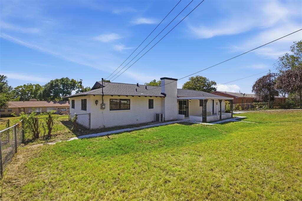 2313 Clearview Drive, Fort Worth, TX 76119 Expansive grassy yard with chain-link fencing, white exterior, covered patio, and attached chimney