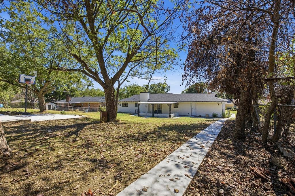 2313 Clearview Drive, Fort Worth, TX 76119 Expansive yard with mature trees, concrete pathway, and a basketball court