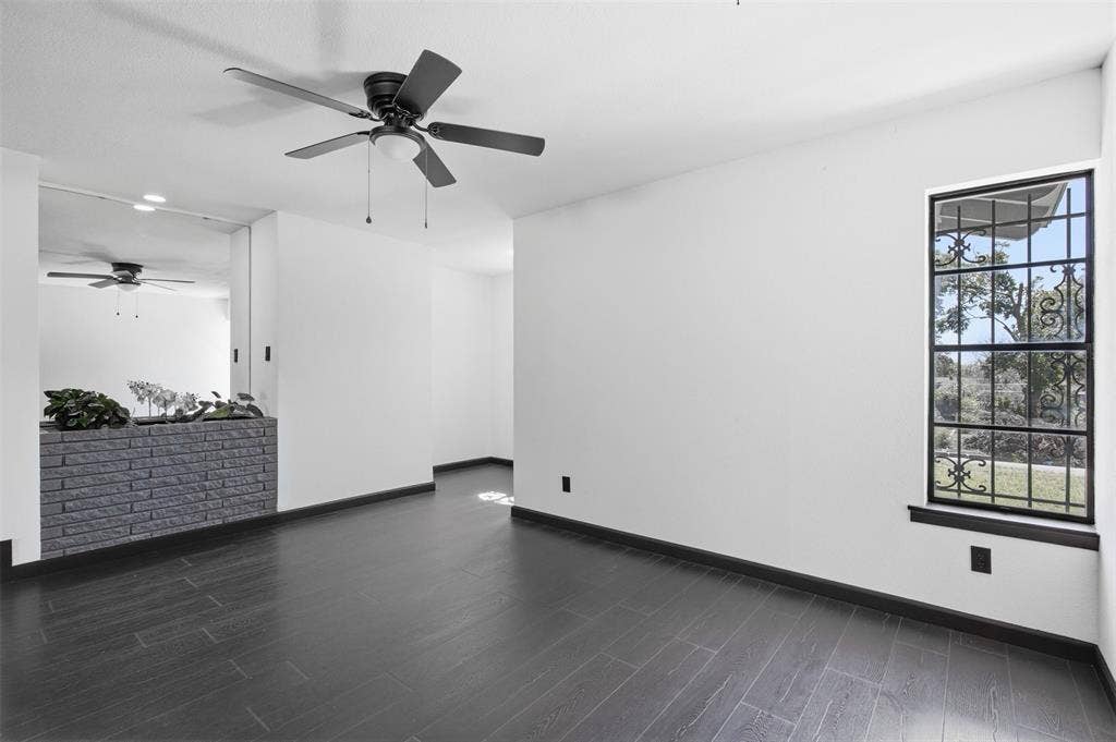 2313 Clearview Drive, Fort Worth, TX 76119 Dark wood-finish flooring, white walls, black ceiling fan, black window trim, and a decorative security grill