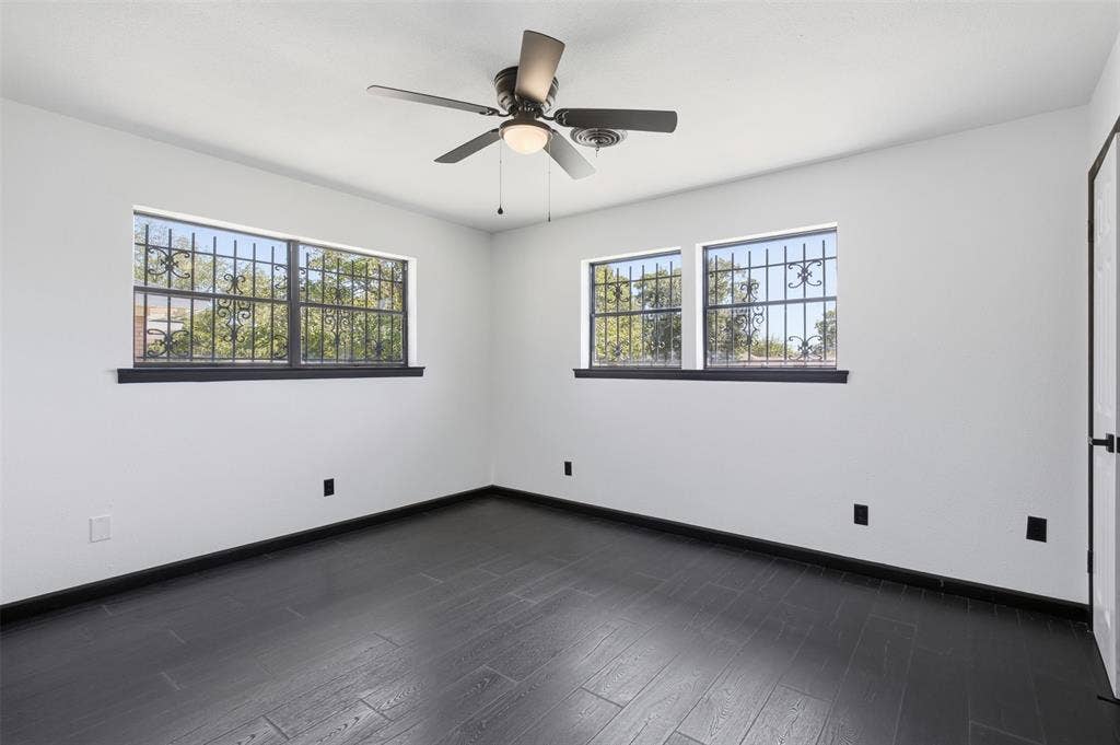2313 Clearview Drive, Fort Worth, TX 76119 Wood-finish flooring, two windows with decorative ironwork, and a ceiling fan with integrated lighting