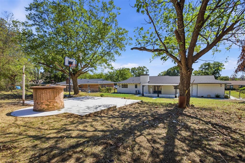 2313 Clearview Drive, Fort Worth, TX 76119 Expansive backyard featuring a concrete patio, a built-in brick fire pit, and mature trees providing natural shade