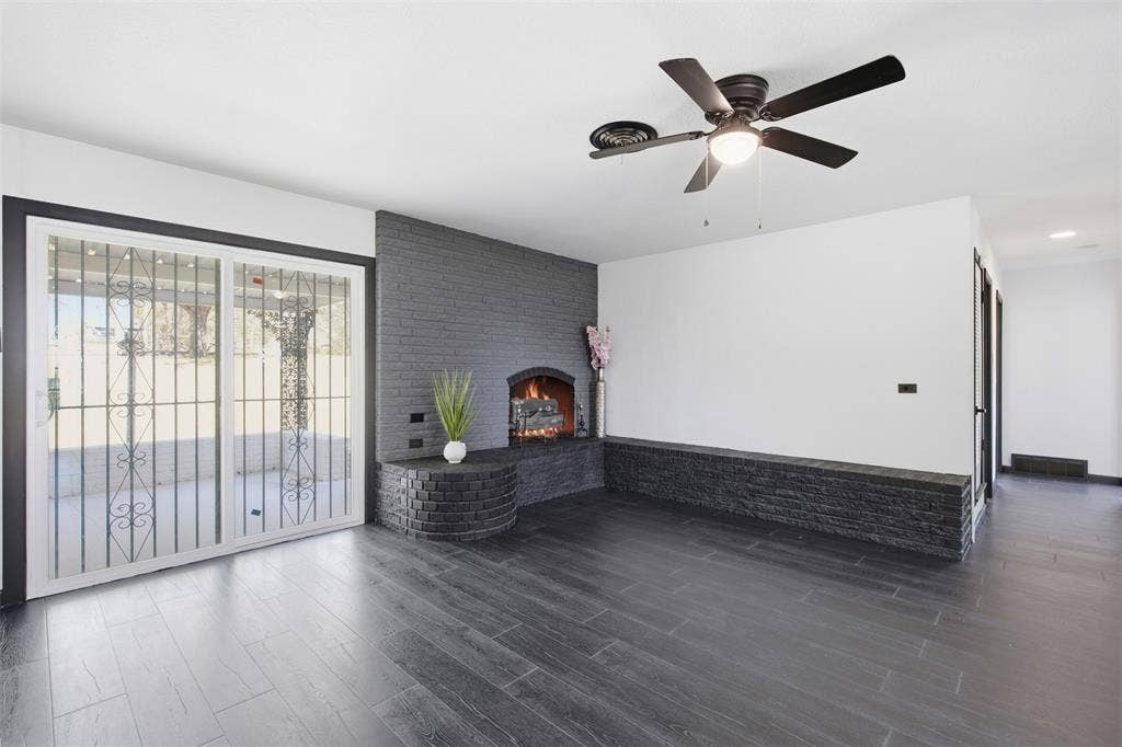 2313 Clearview Drive, Fort Worth, TX 76119 Spacious living area featuring a fireplace, dark wood-finish flooring, and a ceiling fan with integrated lighting