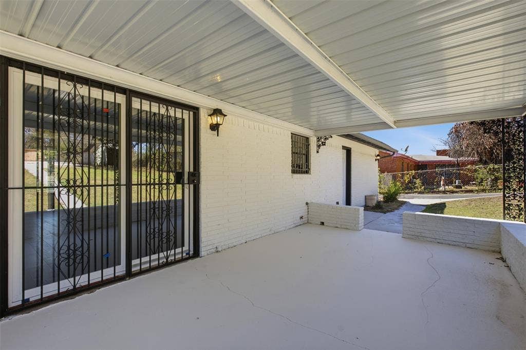 2313 Clearview Drive, Fort Worth, TX 76119 Covered patio featuring a white painted brick exterior, outdoor wall sconce, and sliding glass doors with decorative security bars