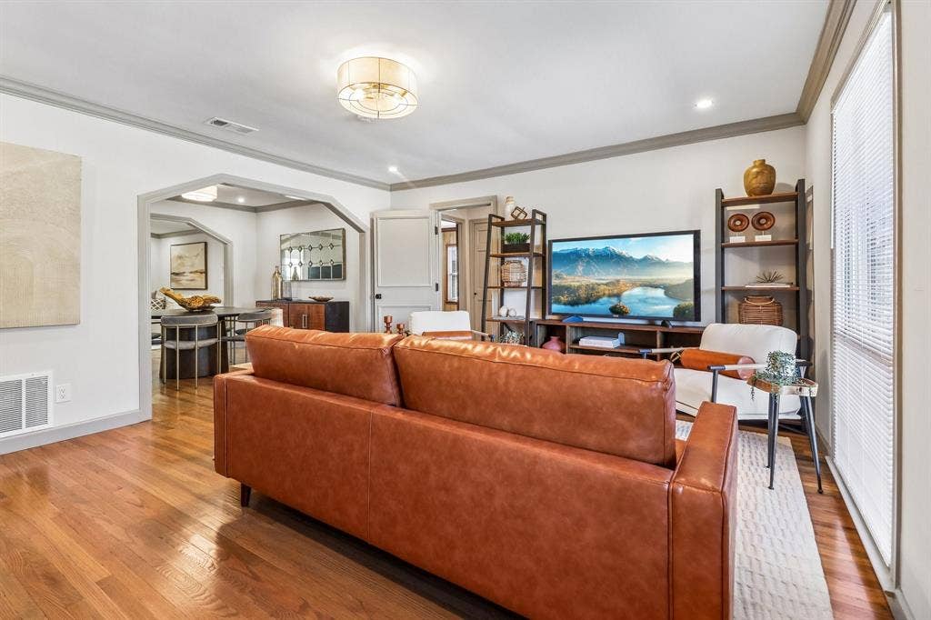 Hardwood flooring throughout, arched doorway, recessed lighting, crown molding, and a drum ceiling light fixture