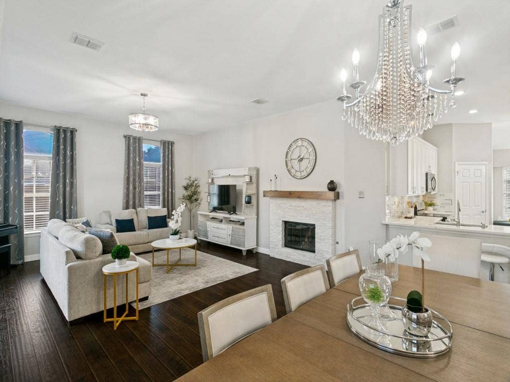 Hardwood-finish flooring throughout, a stone-surround fireplace with a wood mantel, a crystal chandelier, and recessed lighting
