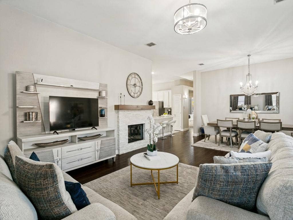 Open-concept living space featuring wood-finish flooring, a stacked stone fireplace with a wood mantel, and an attached dining area