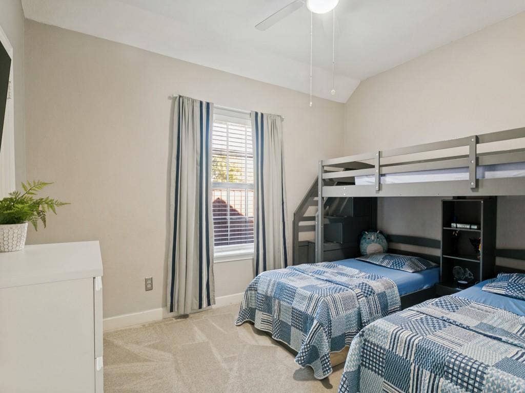 Vaulted ceiling, ceiling fan, window with blinds, light gray wall paint, and gray carpet flooring
