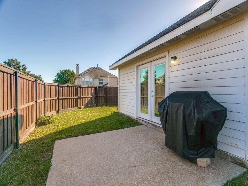 Fenced backyard featuring a concrete patio, a manicured lawn, and double-pane glass doors