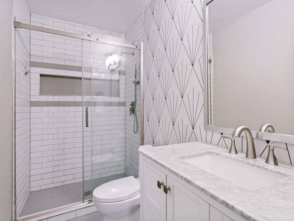 Glass-enclosed shower with subway tile, built-in niche, and mosaic accent