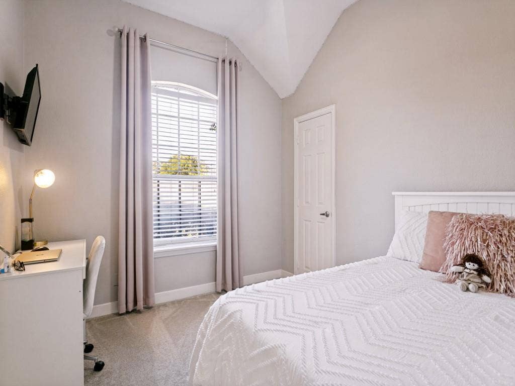 Vaulted ceiling, arched window with blinds, panel door, and soft grey wall tones