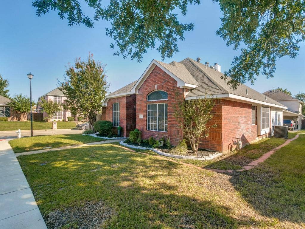 Brick exterior with an arched window, white trim accents, and a shingled roof