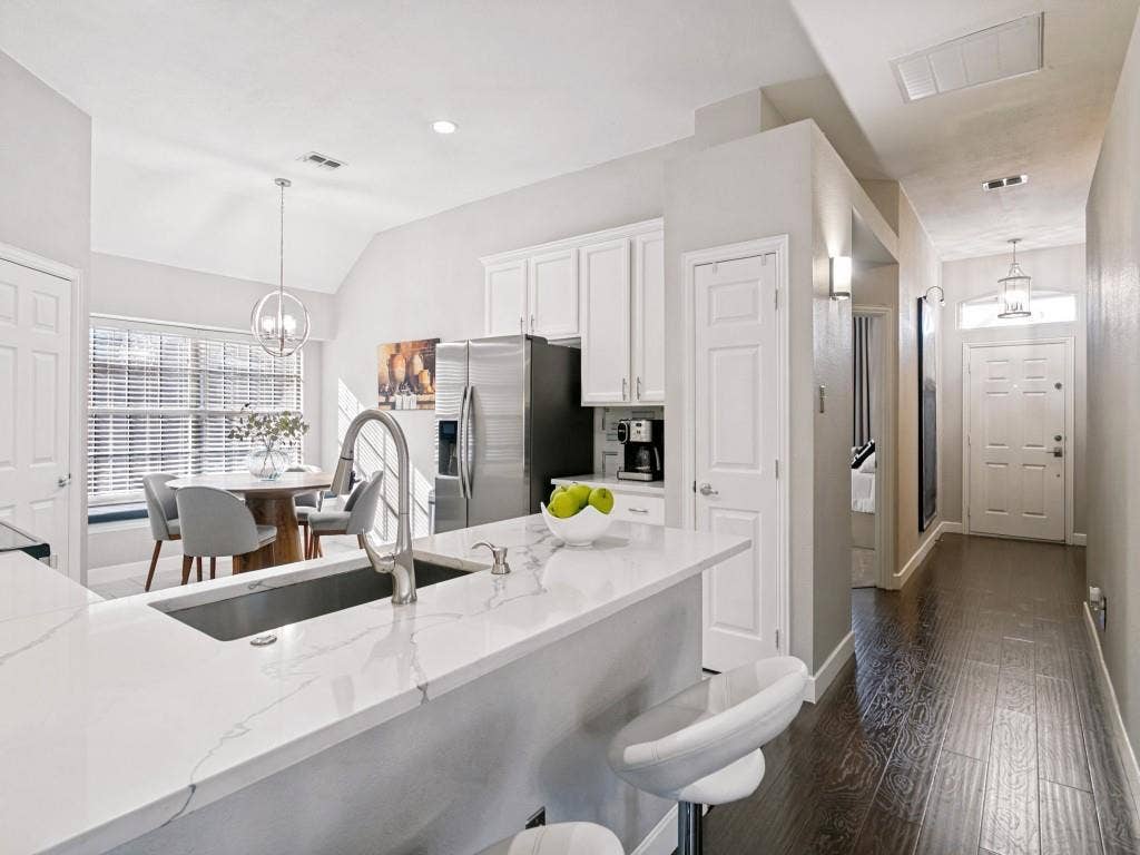 Kitchen with white cabinetry, stainless steel appliances, and a central island featuring a sink and white stone countertop