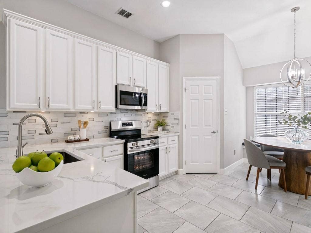 Contemporary kitchen featuring white cabinetry, stainless steel appliances, and sleek countertops
