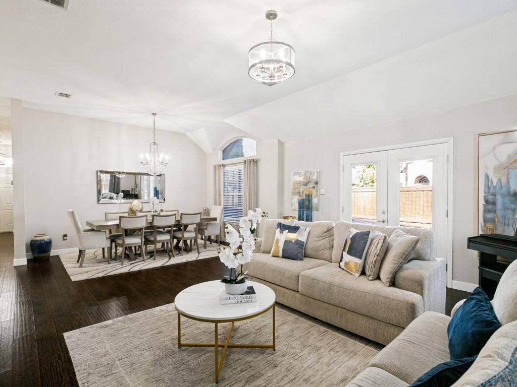Vaulted ceilings with a contemporary chandelier, wood-finish flooring, and French doors