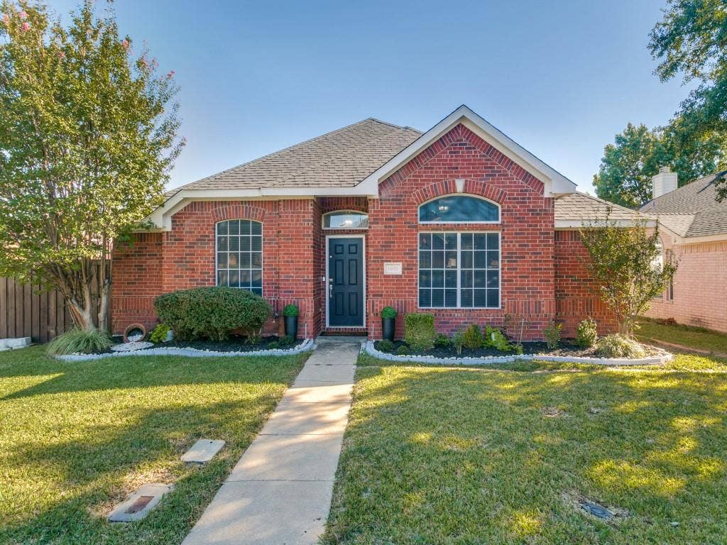 Red brick exterior with arched window accents, gabled roofline, and front entry door