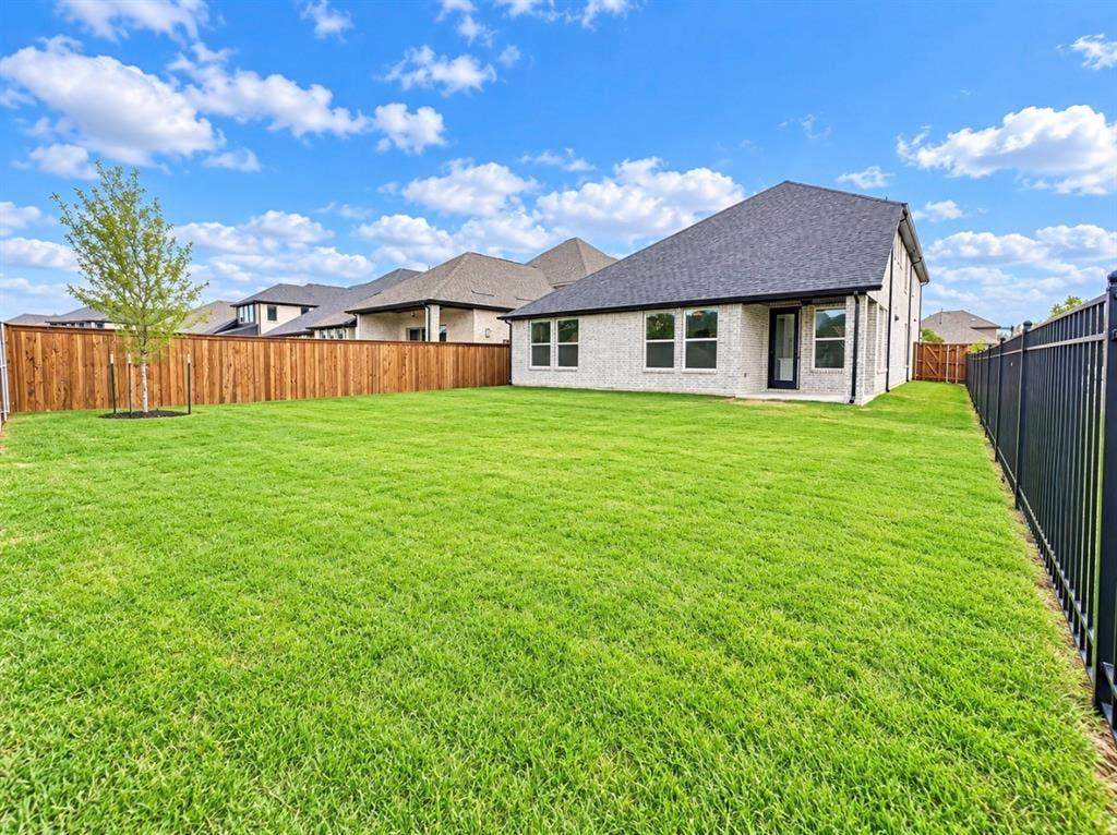 1129 Bradford Street, Celina, TX 75009 Expansive backyard featuring a manicured lawn, established privacy fencing, and a newly planted tree