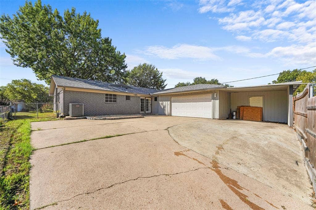 6606 Coleshire Drive, Dallas, TX 75232 Gray brick exterior with a two-car garage, covered carport, and concrete drive