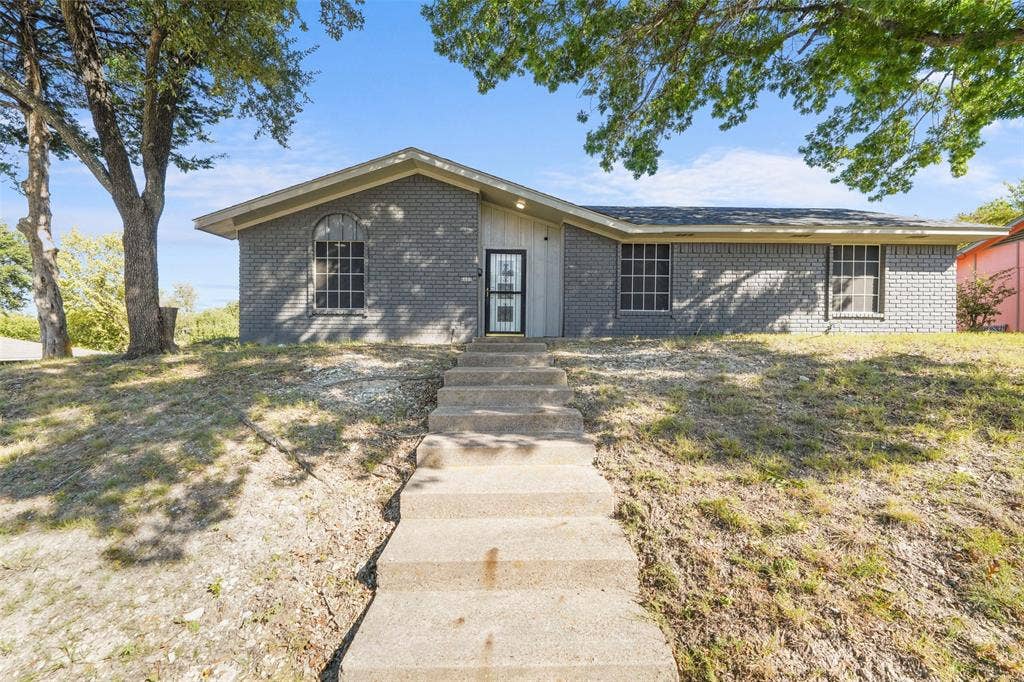 6606 Coleshire Drive, Dallas, TX 75232 Brick exterior with a gabled roofline, featuring an arched window and a security screen door