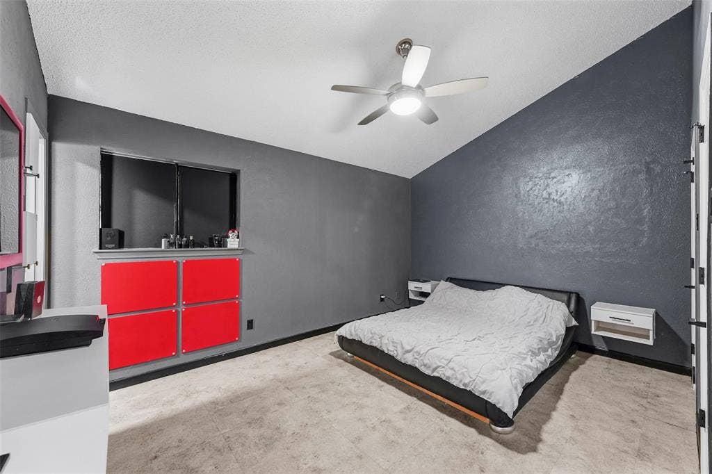 6606 Coleshire Drive, Dallas, TX 75232 Sloped ceiling, ceiling fan with integrated lighting, window with built-in storage below, red wall-mounted cabinetry, and wood-finish flooring