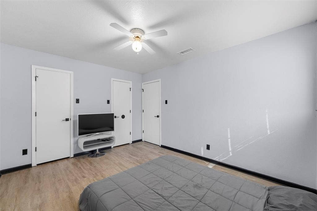 6606 Coleshire Drive, Dallas, TX 75232 Wood-finish flooring, three white panel doors, and a ceiling fan with integrated lighting