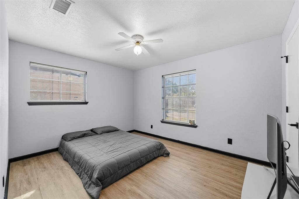 6606 Coleshire Drive, Dallas, TX 75232 Wood-finish flooring, white walls, and two windows with black trim