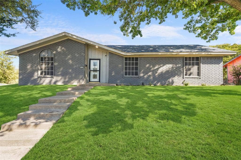 6606 Coleshire Drive, Dallas, TX 75232 Brick exterior facade with a prominent arched window, concrete entry stairs, and a security screen door