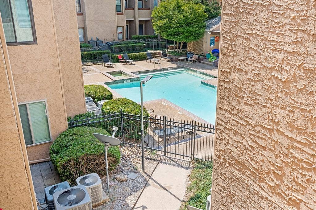 5550 Spring Valley Road, #C21, Dallas, TX 75254 Community swimming pool with an integrated spa, surrounded by a black metal fence and concrete decking